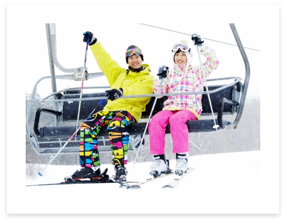 スキー場でリフトに乗る男女の画像